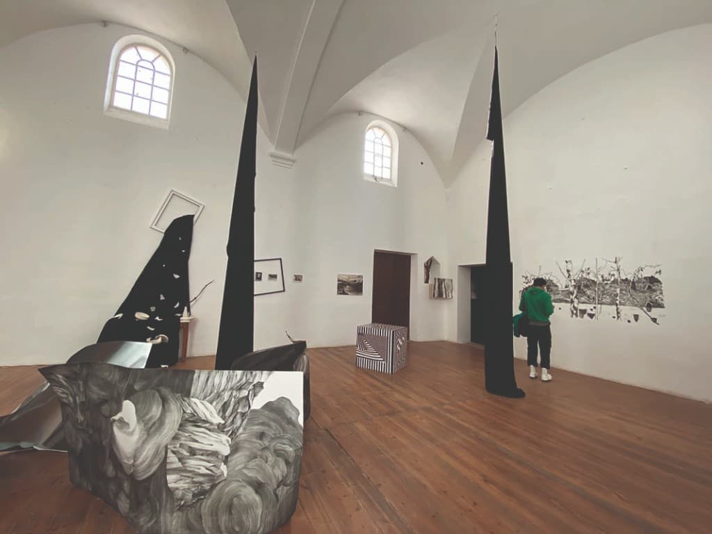 Salle voûtée du couvent aménagée en galerie d'art contemporain avec installations graphiques en noir et blanc.